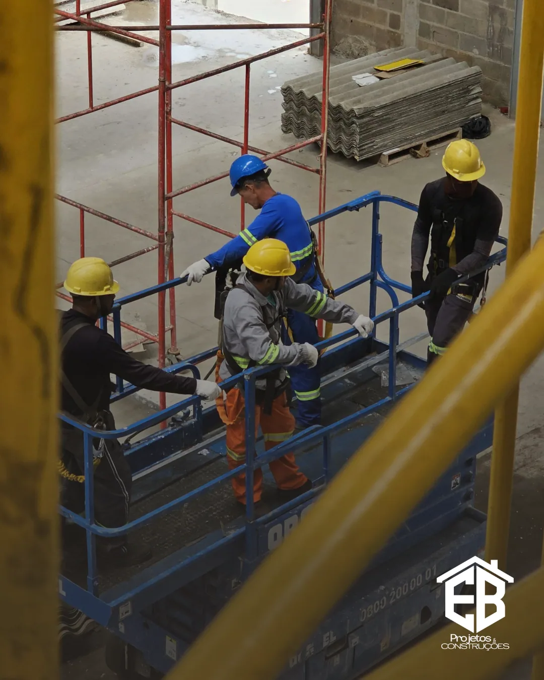 Equipe em plataforma elevatória durante serviço em altura no galpão